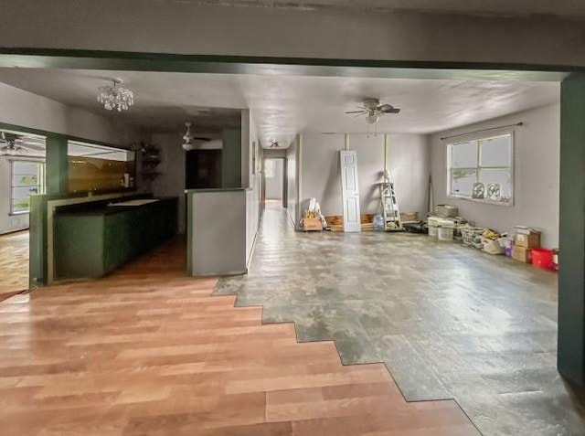 basement with ceiling fan with notable chandelier and light wood-type flooring