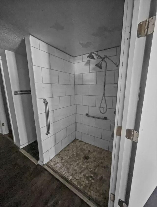 bathroom featuring a tile shower, concrete floors, and a textured ceiling