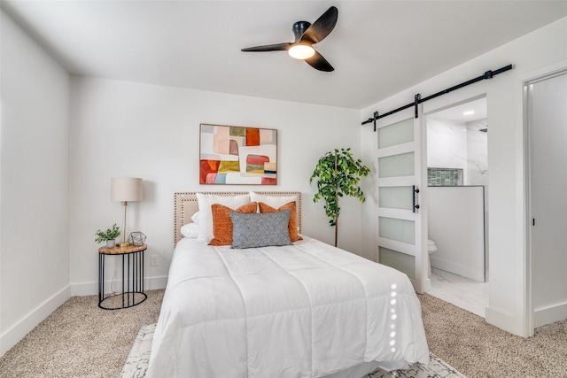 carpeted bedroom with ceiling fan, a barn door, and ensuite bathroom