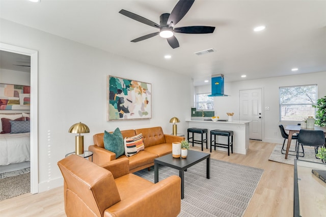 living room with ceiling fan, plenty of natural light, and light hardwood / wood-style floors