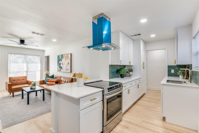 kitchen with decorative backsplash, sink, exhaust hood, white cabinetry, and stainless steel range with electric cooktop