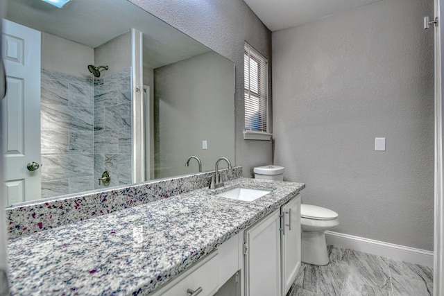 bathroom featuring a tile shower, vanity, and toilet