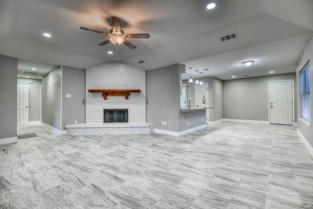 unfurnished living room featuring a brick fireplace, ceiling fan, lofted ceiling, and sink