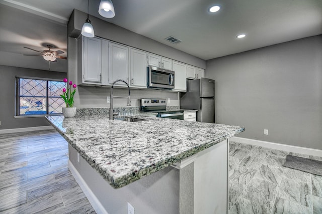 kitchen featuring sink, stainless steel appliances, kitchen peninsula, pendant lighting, and white cabinets