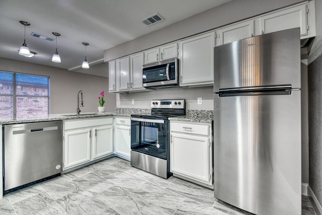 kitchen with light stone countertops, appliances with stainless steel finishes, white cabinetry, and sink