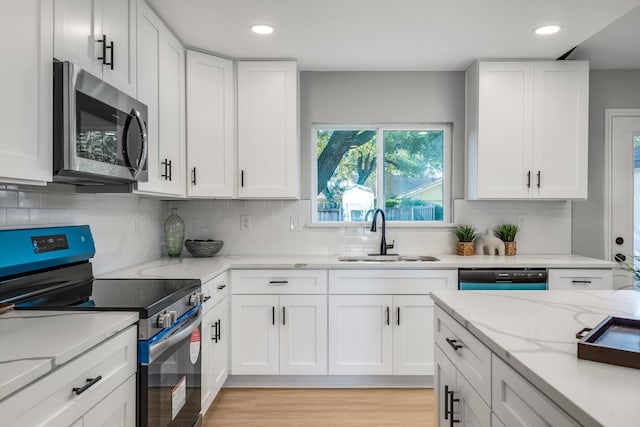 kitchen featuring light stone countertops, sink, stainless steel appliances, tasteful backsplash, and white cabinets