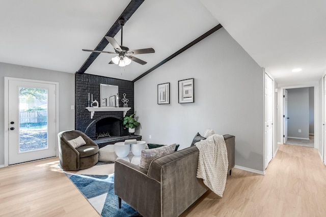 living room with lofted ceiling with beams, light hardwood / wood-style floors, a fireplace, and ceiling fan