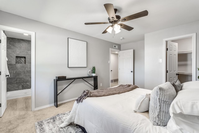 bedroom featuring ceiling fan, light colored carpet, a walk in closet, and a closet