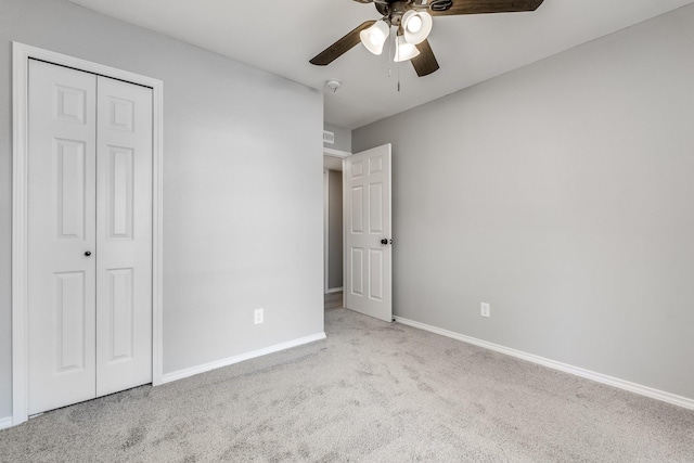 unfurnished bedroom featuring ceiling fan, light carpet, and a closet