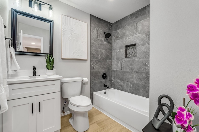 full bathroom featuring hardwood / wood-style flooring, tiled shower / bath combo, toilet, and vanity