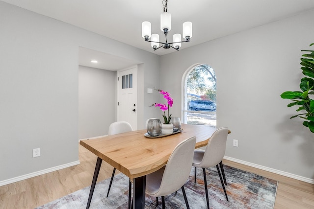 dining space with light hardwood / wood-style floors and a notable chandelier