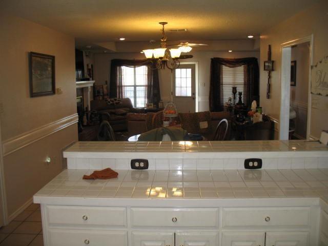 kitchen with hanging light fixtures, white cabinetry, tile counters, and a chandelier