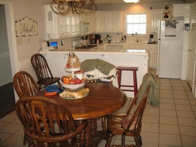 tiled dining room with a chandelier