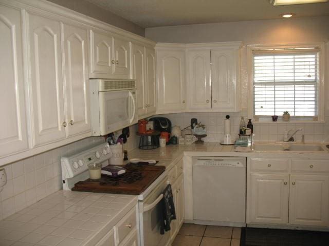 kitchen featuring light tile patterned floors, white appliances, white cabinetry, and sink