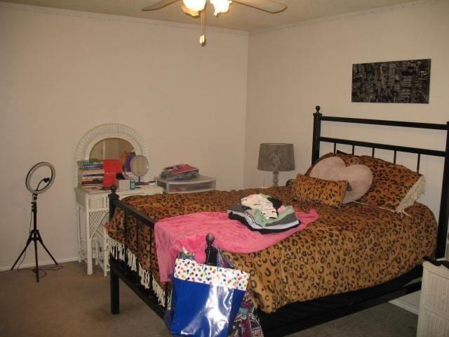 bedroom with ceiling fan, ornamental molding, and carpet