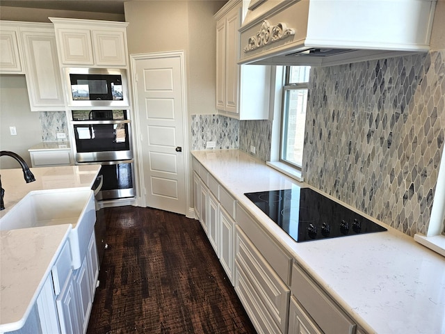 kitchen with white cabinetry, black electric cooktop, premium range hood, and built in microwave