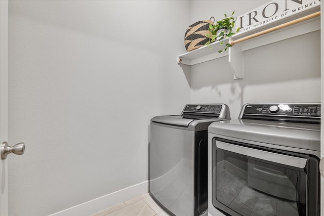 washroom with laundry area, light tile patterned floors, baseboards, and washer and clothes dryer