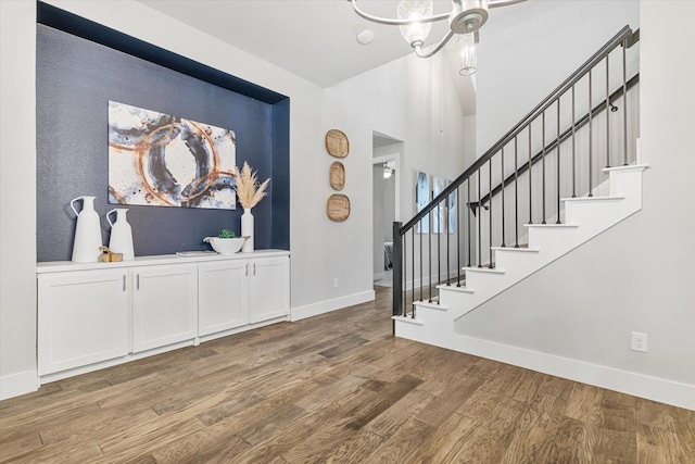 entryway featuring a chandelier, stairs, baseboards, and wood finished floors