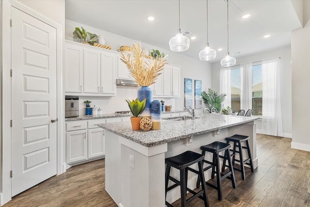 kitchen featuring a sink, wood finished floors, and white cabinets