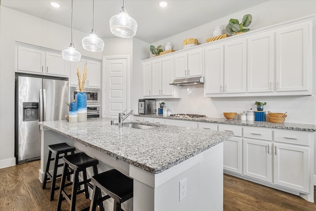 kitchen with dark wood finished floors, a sink, under cabinet range hood, appliances with stainless steel finishes, and white cabinetry