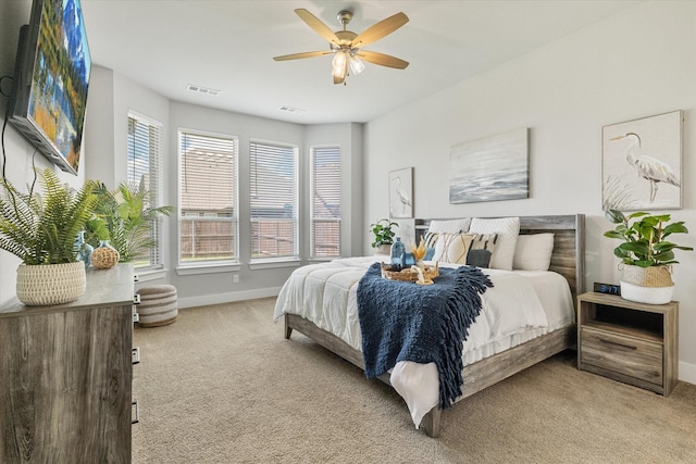 bedroom with a ceiling fan, light colored carpet, visible vents, and baseboards