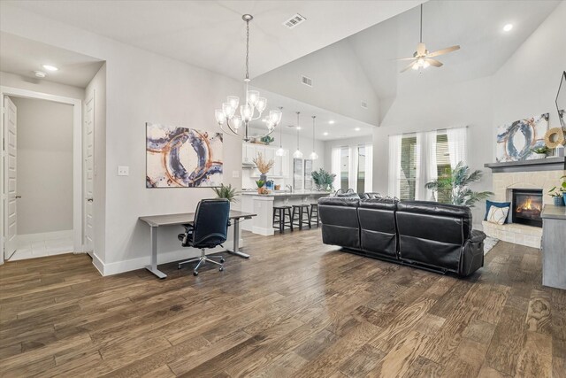 living area featuring wood finished floors, baseboards, visible vents, high vaulted ceiling, and a fireplace