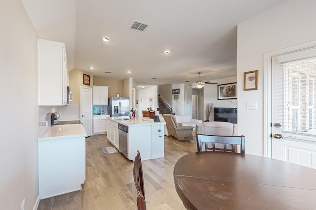 dining area with light wood finished floors, stairway, visible vents, and ceiling fan