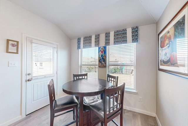 dining room with a healthy amount of sunlight, light wood finished floors, and lofted ceiling