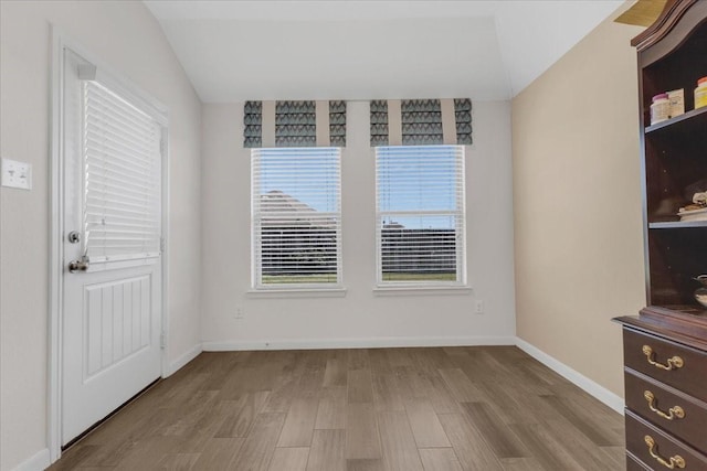 interior space with lofted ceiling, baseboards, and wood finished floors