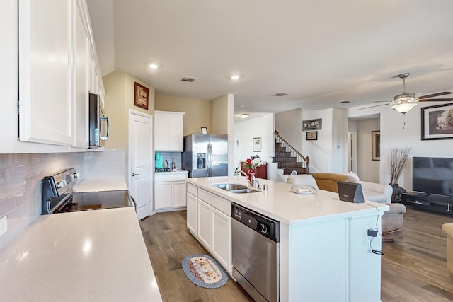 kitchen featuring white cabinets, decorative backsplash, an island with sink, and stainless steel appliances