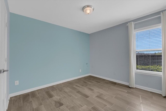 spare room featuring baseboards and wood finished floors
