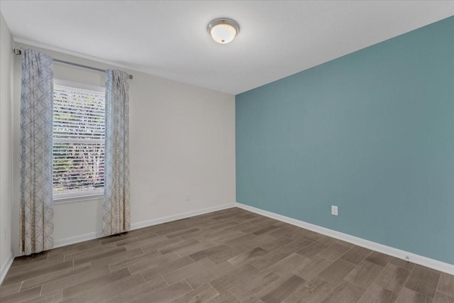 unfurnished room featuring baseboards and wood finish floors