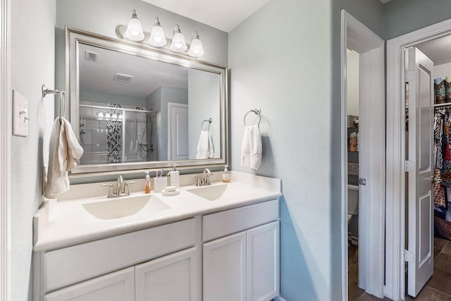 bathroom with a sink, a spacious closet, a shower stall, and double vanity