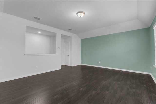 empty room with dark wood-style flooring, baseboards, vaulted ceiling, and visible vents