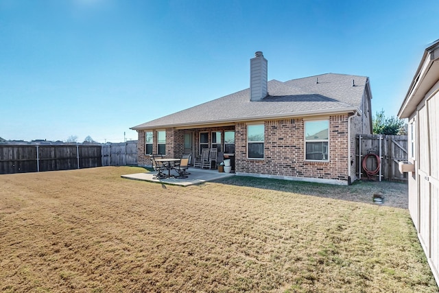 rear view of house with a patio, brick siding, a yard, and a fenced backyard