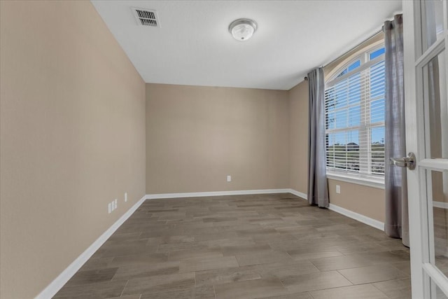 spare room with visible vents, baseboards, and wood finished floors