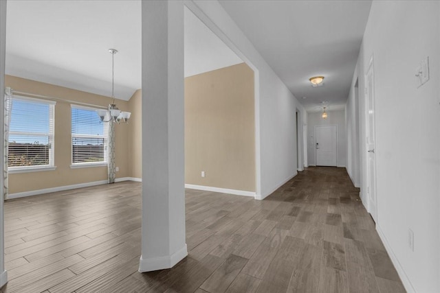 hallway with a chandelier, baseboards, and wood finished floors