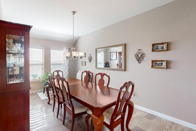 dining area featuring vaulted ceiling and a notable chandelier