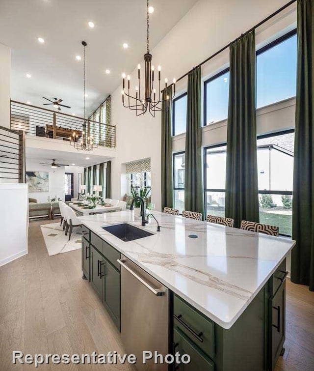 kitchen with light stone counters, sink, an island with sink, and dishwasher