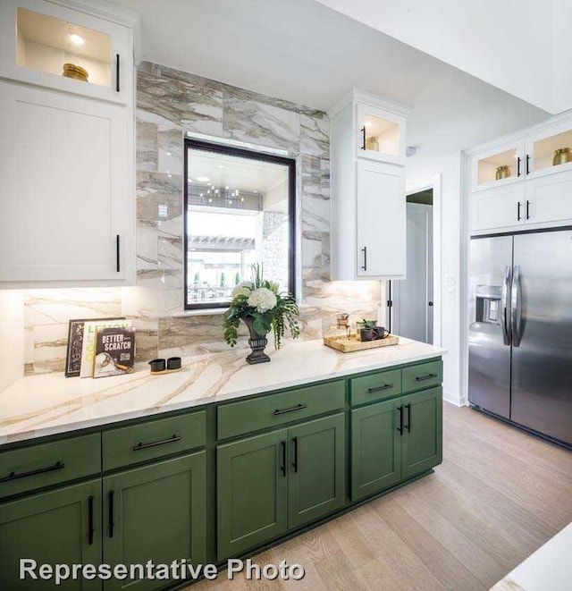 kitchen featuring light hardwood / wood-style flooring, stainless steel fridge, green cabinets, decorative backsplash, and white cabinets