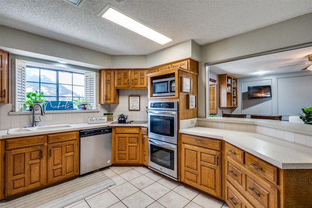 kitchen with stainless steel appliances, tasteful backsplash, sink, and light tile patterned floors