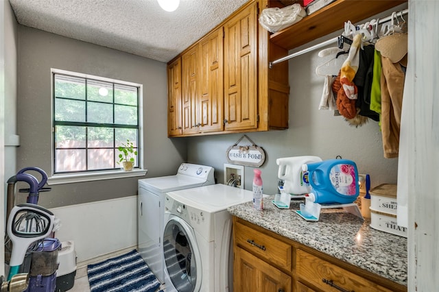 clothes washing area featuring cabinets, a textured ceiling, and washing machine and clothes dryer