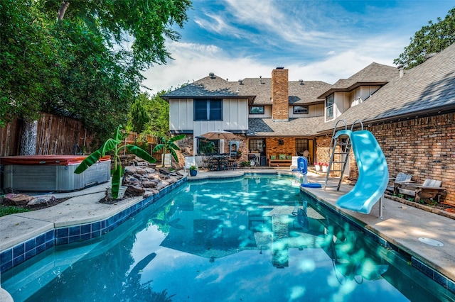 view of pool with a hot tub, a water slide, and a patio area