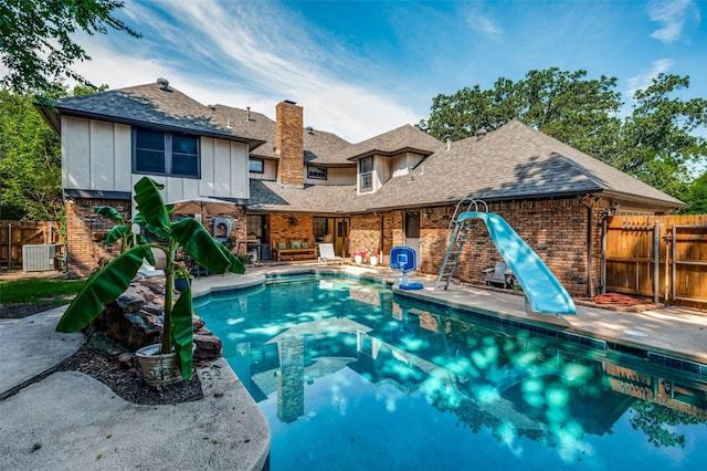 view of pool featuring a water slide, a patio area, and central air condition unit