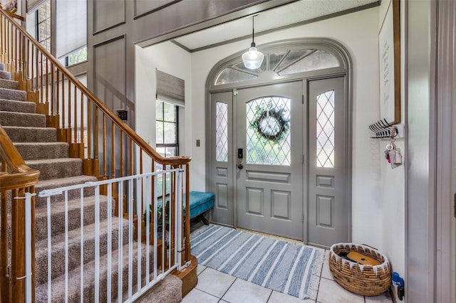 entryway with light tile patterned flooring and crown molding