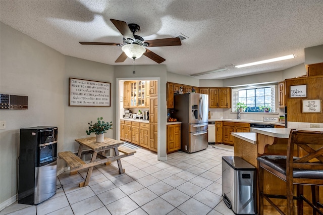 kitchen featuring a breakfast bar, sink, a wood stove, light tile patterned floors, and stainless steel appliances