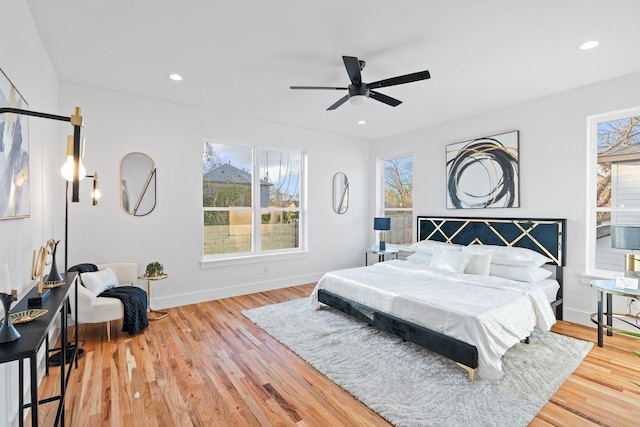 bedroom with hardwood / wood-style flooring, ceiling fan, and multiple windows