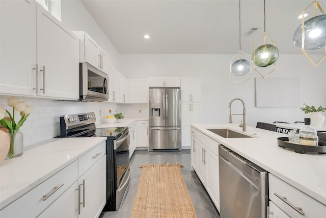 kitchen featuring white cabinetry, sink, backsplash, pendant lighting, and appliances with stainless steel finishes