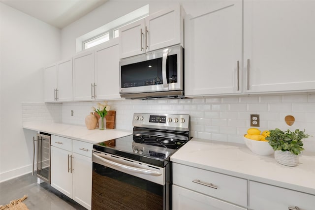 kitchen featuring white cabinets, wine cooler, tasteful backsplash, light stone counters, and stainless steel appliances