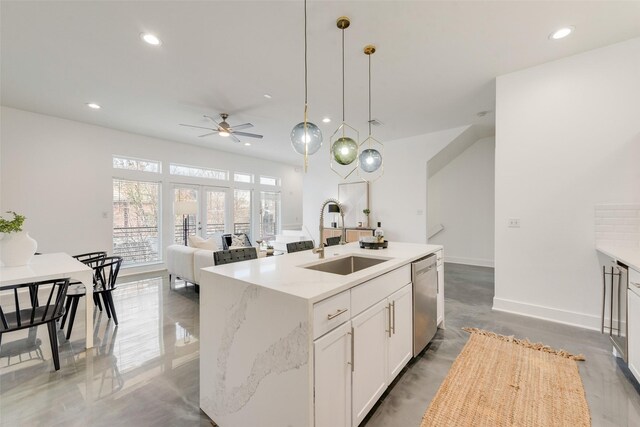 kitchen with light stone countertops, sink, stainless steel dishwasher, an island with sink, and decorative light fixtures